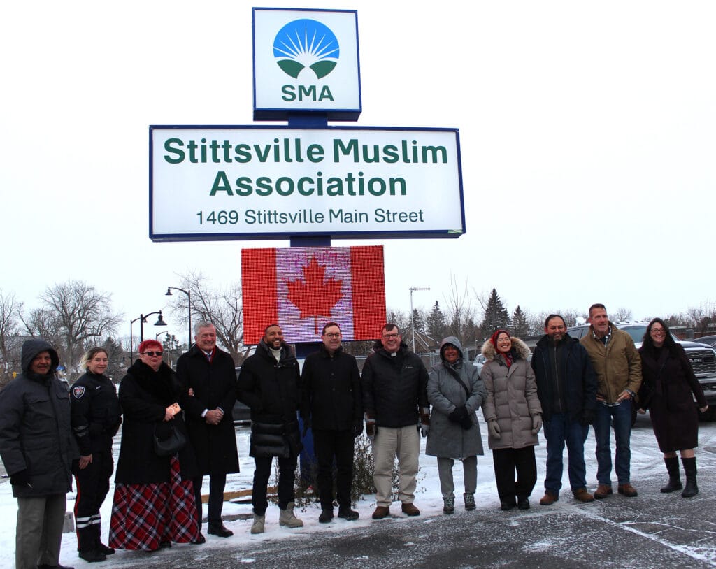 Group photo in front of the Stittsville Muslim Association sign