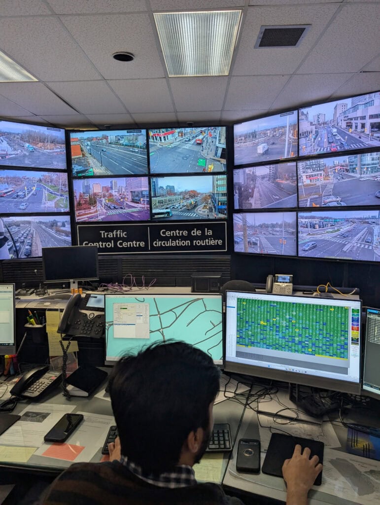 An operator sits in front of a computer with screens in the background