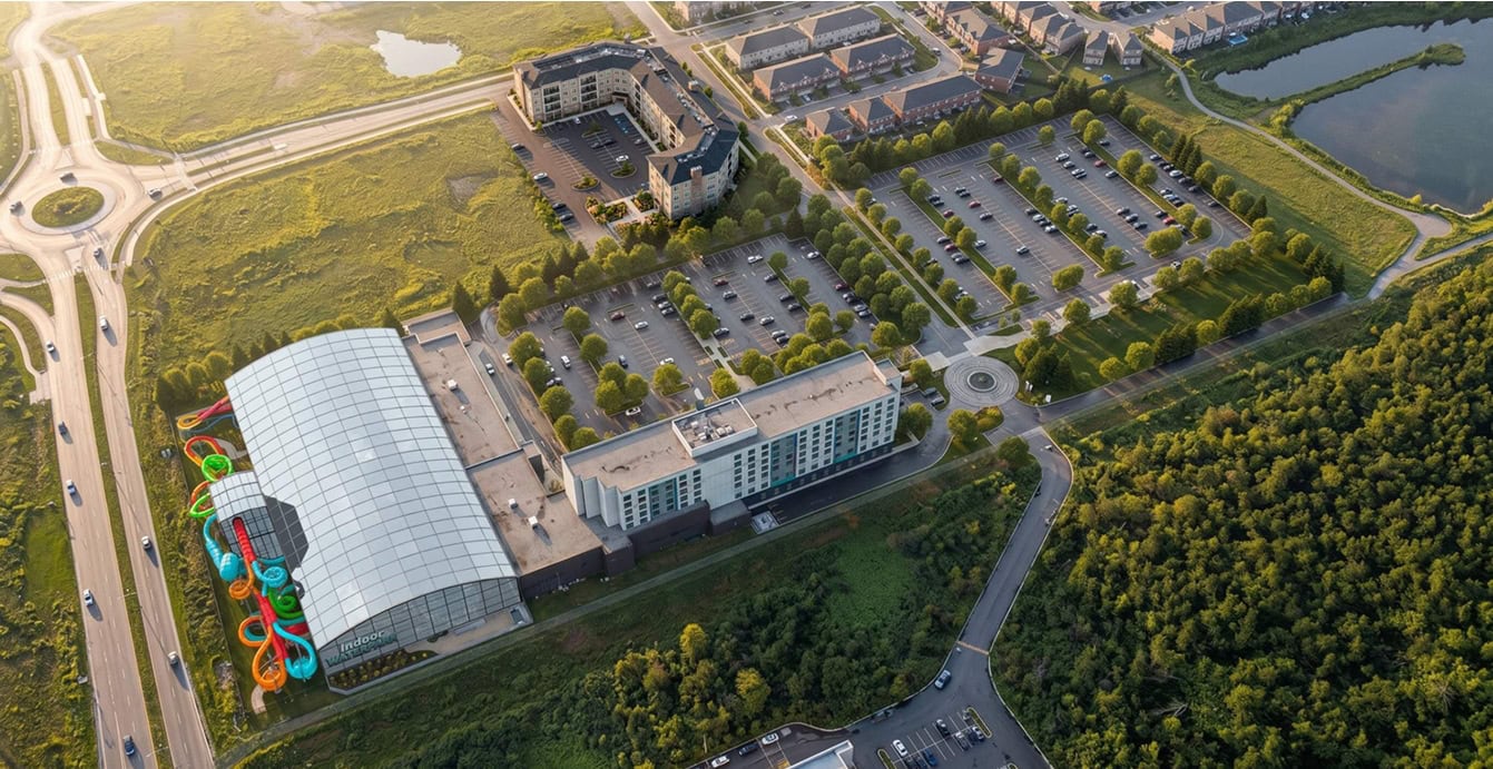 Aerial view of a recreational complex beside a suburban development and an arterial road